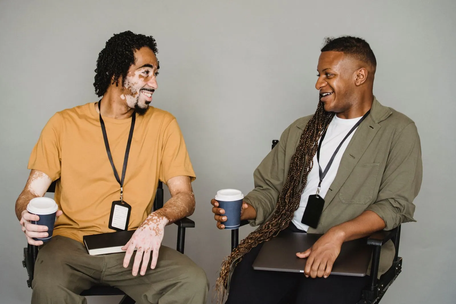 Deux jeunes hommes qui discutent en souriant, un café à la main